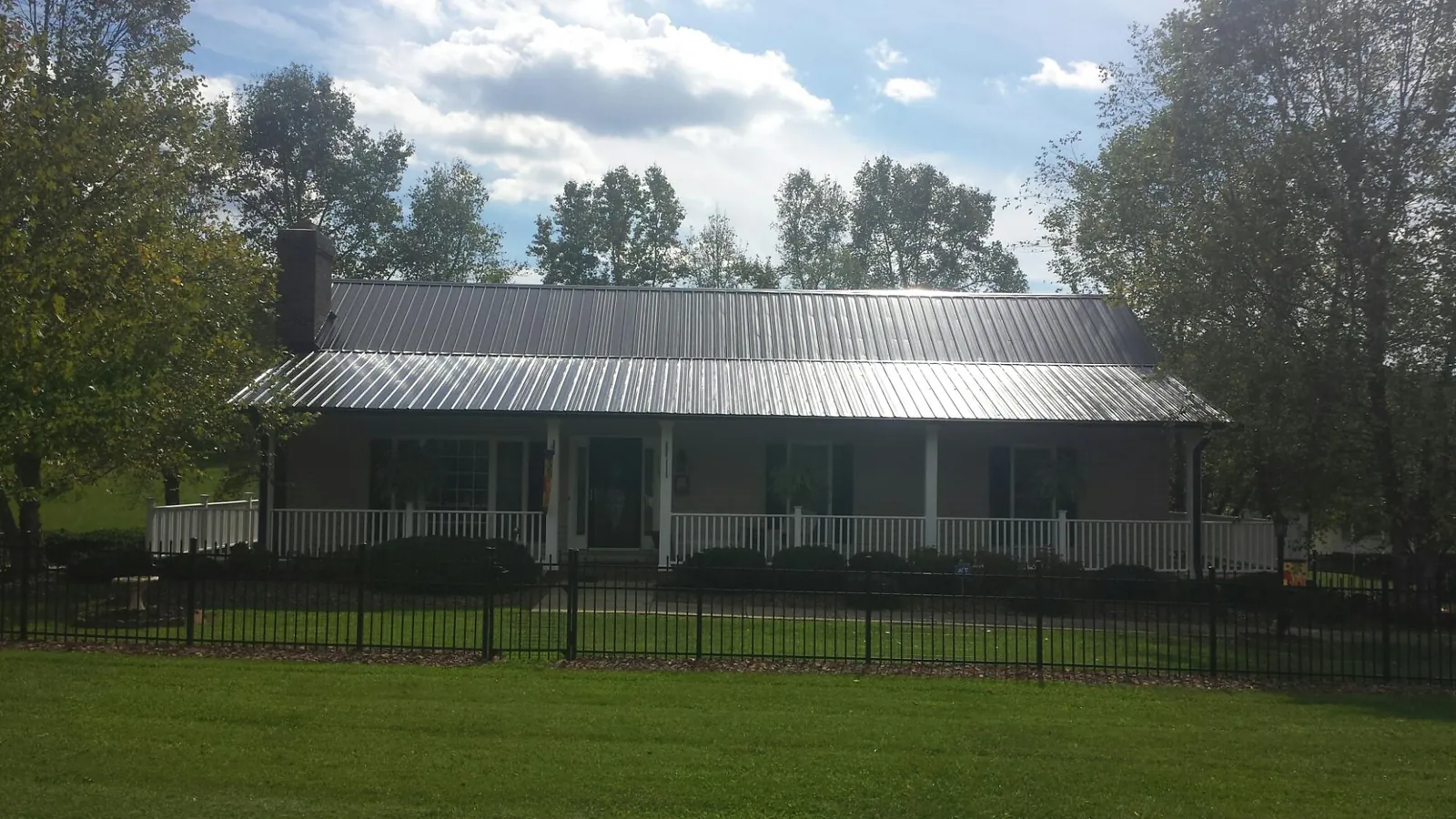 Gray metal roof on a brick ranch with a full width front porch — Gutter Guard Installation work by our crew in New Haven